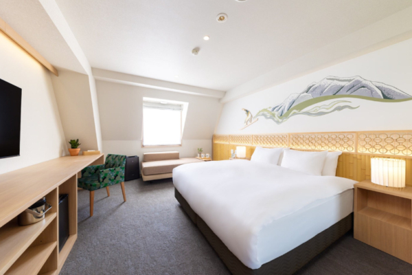The Happo deluxe hotel room bed, sofa seating, desk and chair, and decorative wall | Happo Village, Hakuba