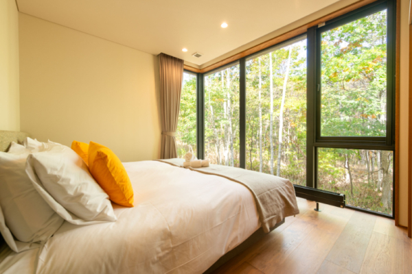 Yuzen fourth bedroom with king size bed, wooden floors and black-out curtains, full-height windows with forest views | Kabayama, Niseko